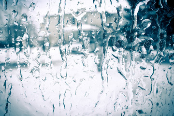 Rain drops flow down on glass. Streams of water flowing on the glass..