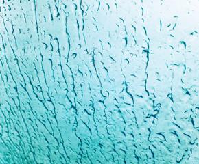 Rain drops flow down on glass. Streams of water flowing on the glass..