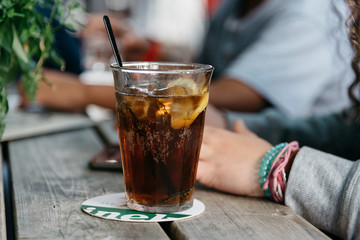 Refreshing glass of cola on wooden table in a bar - obrazy, fototapety, plakaty