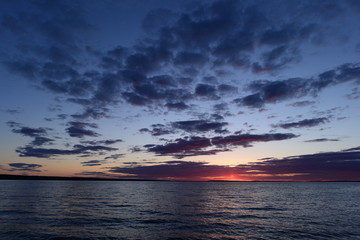 Flash of a bright red sunset on the horizon in the sky above the lake