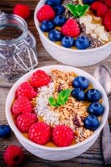 Peach smoothie bowls with raspberries, blueberries, chia seeds and granola