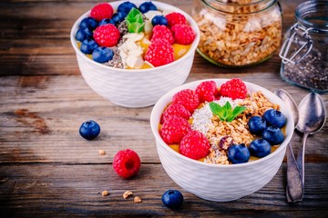Mango smoothie bowls with raspberries, blueberries, chia seeds and granola