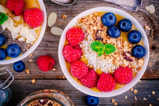 Peach smoothie bowls with raspberries, blueberries, chia seeds and granola
