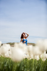 Attractive beautiful woman in blue dress in tulip field in sunny summer day. Beautiful girl in springtime