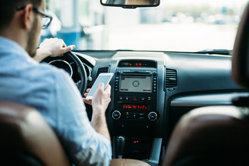 Businessman ignoring safety and texting onmobile phone while driving