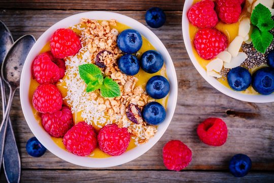 Mango smoothie bowl with raspberries, blueberries, granola and coconut