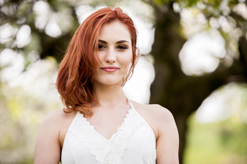 Naklejka premium Gorgeous redhead woman in outdoor photo in sunny summer day. Beautiful girl in springtime