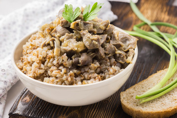 Buckwheat porridge and meat in a white bowl on a wooden table.