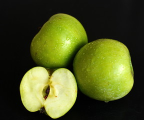 Fototapeta na wymiar green apple slice with drops of water on black background