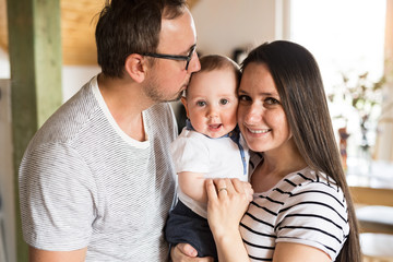 Fototapeta premium Beautiful young parents holding their cute baby son