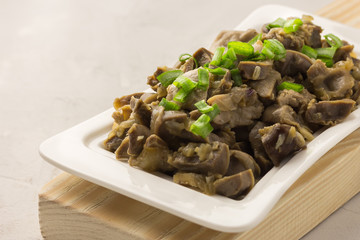 Meat and green onion in a white plate on wooden table. Spicy meat and green chives in a white plate. Healthy food.