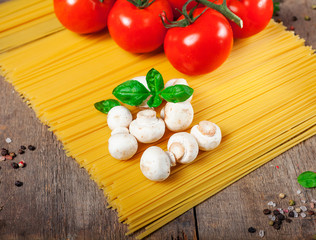 Italian dry pasta spaghetti with tomatoes and fresh herbs on a dark wooden background, selective focus