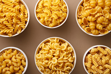 Pasta variations in bowls. Top view of raw Italian pastas (fusilli, conchiglie, pipe, elicodali, creste di galo