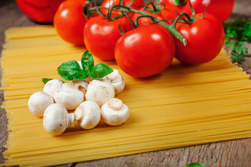 Italian dry pasta spaghetti with tomatoes and fresh herbs on a dark wooden background, selective focus