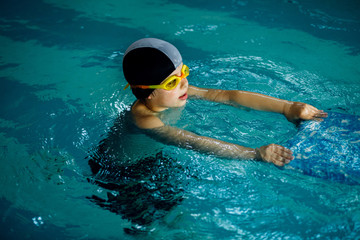 The boy who learns to swim with board in the pool