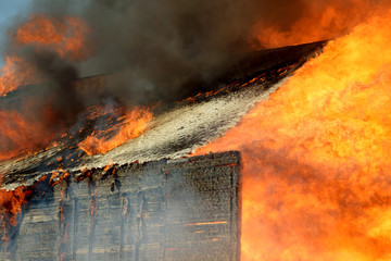 House burning on fire. Building covered by flame. Flaming wooden construction.