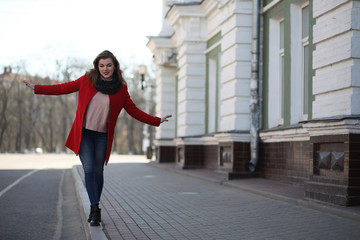 Obraz premium Pretty girl on a walk in red coat in the city
