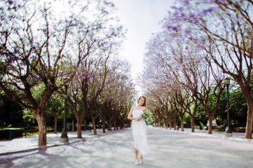 Blonde woman in blossom tree alley white dress summer feeling