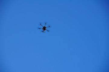 kleine schwarze Dhrone am blauen Himmel
