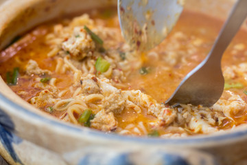 Tom Yum Kung with noodles and seafood, popular Thai food. Tom Yum Goong Spicy Sour Soup on wooden table top view, Thai local food