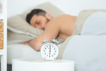 man asleep in bed alarm clock ready six oclock
