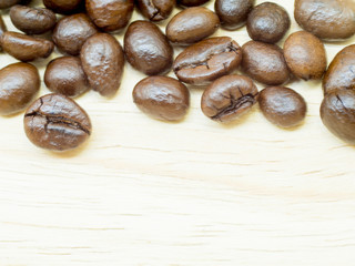 The group of thin coffee beans is on light wood background.