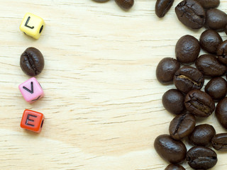 A cluster of thin coffee beans on light wood floor. There is a love letter. Consisting of letters and coffee
