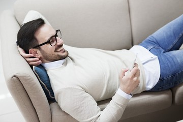 Handsome young man with glasses smiling and using phone