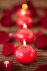 Fototapeta na wymiar Red wax candles surrounded with rose petals