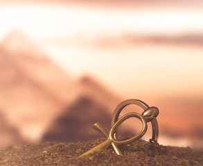 The Egyptian ankh is a cross in the sand against the backdrop of the Great Pyramids. Photo toned.