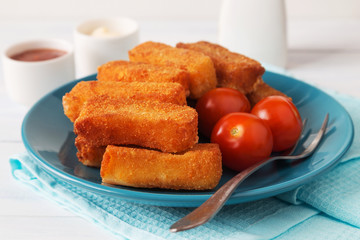 Fried cheese sticks with tomatoes, a fork and sauces