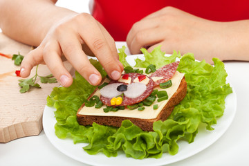 Child hands making a funny creative sandwich