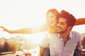 Couple in love cuddling while enjoying beautiful urban sunset together