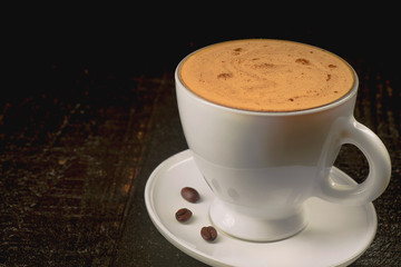 Cup of the bright coffee on the dark background