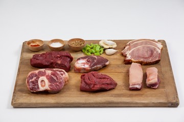 Varieties of meat with spices on wooden board