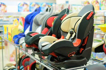 Row of different car safety seats for kids on shlef in kids store