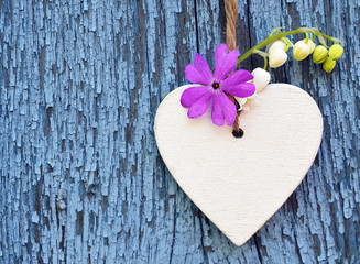 Decorative wooden heart with spring flowers on blue old wooden background.Spring decoration.Selective focus.