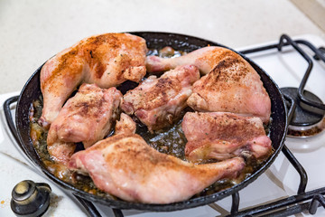 Juicy chicken pieces with spices are fried in a pan in oil on the stove
