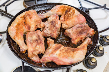 Juicy chicken pieces with spices are fried in a pan in oil on the stove

