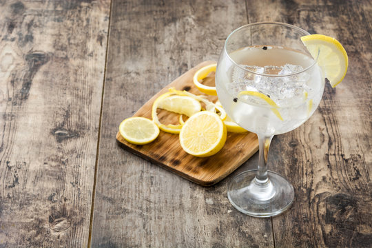 Glass of gin tonic with lemon on wooden background
