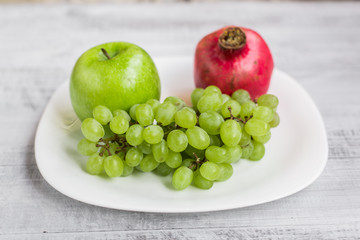 Fresh apples, grapes and pomegranate on the table. Ecological wooden background.