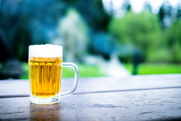 Glass of light beer with foam on a wooden table. Garden party. Natural background. Alcohol. Draft beer. - 150188194