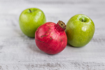 Fresh apples and pomegranate on the table. Ecological wooden background.