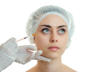 Portrait of a pretty young girl in a special hat on your head which makes injection syringe on face close-up