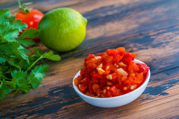 Salsa sauce in small bowl on the wooden rustic table.