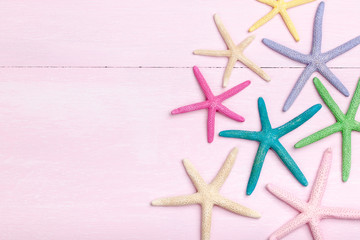 Colorful starfishes on pink wooden background