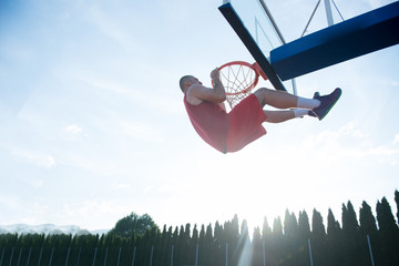 Young man jumping and making a fantastic slam dunk playing stree