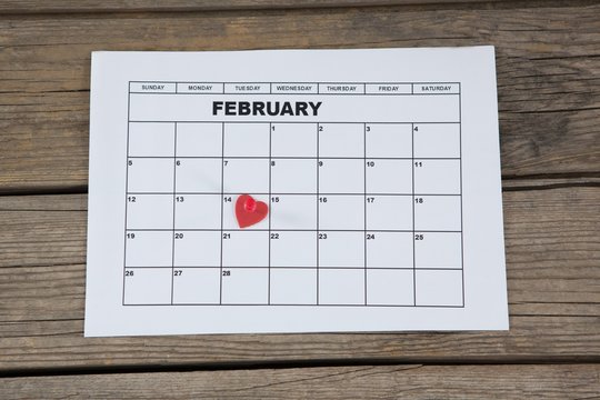 Red heart shape placed on 14th february date of the calendar