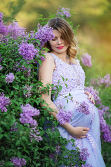 Happy pregnant girl in blossom lilac flowers