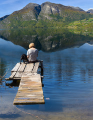 Woman with dog sitting on bridge
